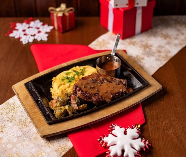 Festive Roasted Turkey, ζουμερό στήθος ψητής γαλοπούλας που περιχύνεται με βελούδινη Port Gravy sauce. Γιορτινή διακόσμηση με κόκκινες και λευκές χιονονιφάδες, δώρα και κόκκινο τραπεζομάντηλο.